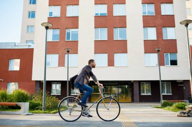 İş elbisesi içinde sakallı Işadamı gün batımında sabah kentsel sokakta çalışmak için retro bisiklet sürme