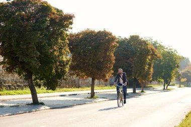 İş elbisesi içinde sakallı Işadamı gün batımında sabah kentsel sokakta çalışmak için retro bisiklet sürme