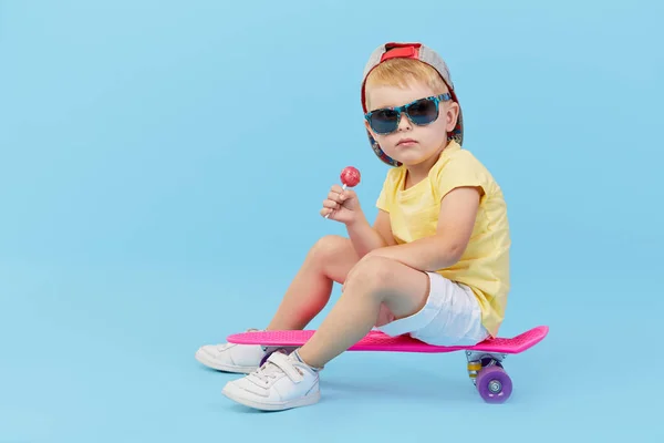 Elegante Criança Menino Óculos Com Skate Divertindo Sobre Fundo Azul — Fotografia de Stock
