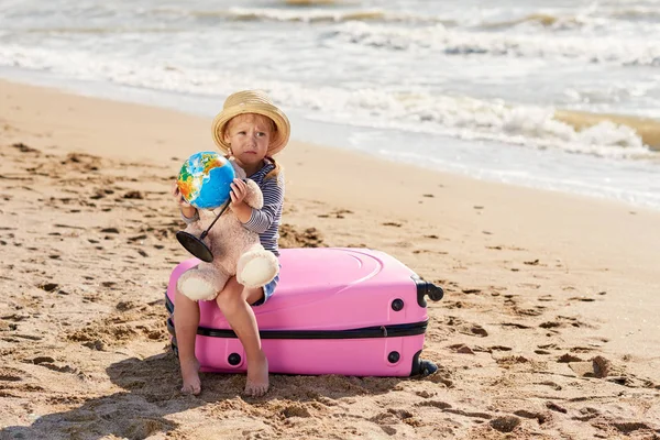 快乐的小女孩在夏天的帽子与手提箱和地球在沙滩 孩子们在圣诞节和新年的暑假里玩得很开心 假日旅游和冒险概念 — 图库照片