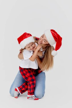 Noel zamanı. Mutlu kucaklaşan aile, anne ve kız, Noel Baba şapkalarıyla oynayan küçük çocuk, beyazlar içinde soyutlanmış. Yeni yıl tatili konsepti