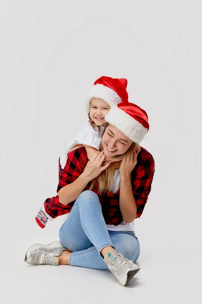 圣诞节的时候 幸福的拥抱家庭 母亲和女儿 小孩戴着圣诞礼帽 孤零零地躺在白色的床上 新年假期的概念 — 图库照片
