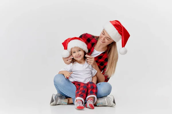 圣诞节的时候 幸福的拥抱家庭 母亲和女儿 小孩戴着圣诞礼帽 孤零零地躺在白色的床上 新年假期的概念 — 图库照片