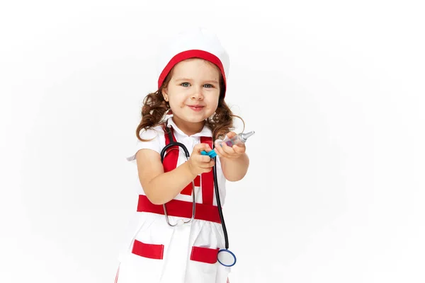 白い背景に聴診器を持って医者の衣装やメガネで幸せなかわいい子供の女の子 彼女の手におもちゃの注射器を保持 予防接種の概念 ストックフォト