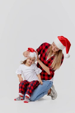 Noel zamanı. Mutlu kucaklaşan aile, anne ve kız, Noel Baba şapkalarıyla oynayan küçük çocuk, beyazlar içinde soyutlanmış. Yeni yıl tatili konsepti