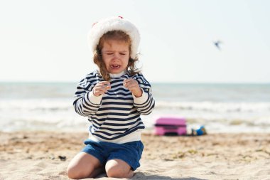 Santa şapka üzgün küçük kız okyanus ayakın tropikal bir plajda ağlıyor. Yakında bavullu bir bavul var, çocuk kayboluyor ve ailesini arıyor. Noel seyahat konsepti