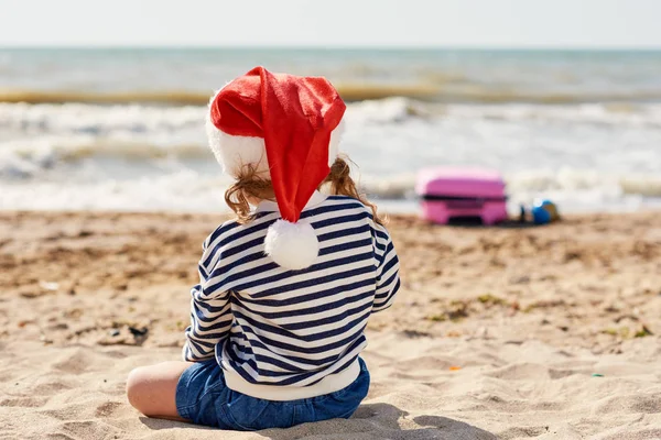 Mała Dziewczynka Kapeluszu Mikołaja Tropikalnej Plaży Pobliżu Oceanu Pobliżu Znajduje — Zdjęcie stockowe