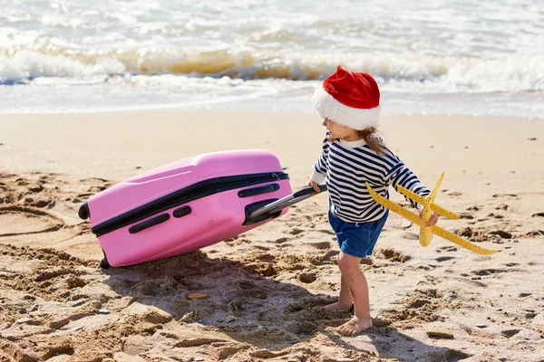 Małe Dziecko Santa Hat Rolkach Walizkę Tropikalnej Plaży Ferie Zimowe — Zdjęcie stockowe