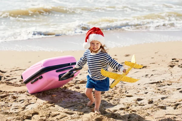 Małe Dziecko Santa Hat Rolkach Walizkę Tropikalnej Plaży Ferie Zimowe — Zdjęcie stockowe