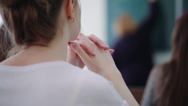 Young woman with golden earrings sits between students — Stock Video