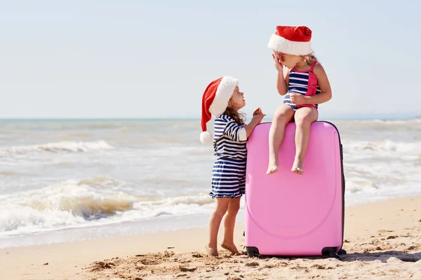 Szczęśliwe Małe Dzieci Dziewczynki Kapeluszach Mikołaja Walizką Globusem Tropikalnej Plaży — Zdjęcie stockowe