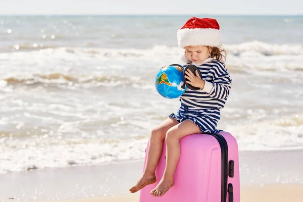 Happy Little Girl Dziecko Santa Kapelusz Walizką Kuli Ziemskiej Tropikalnej — Zdjęcie stockowe