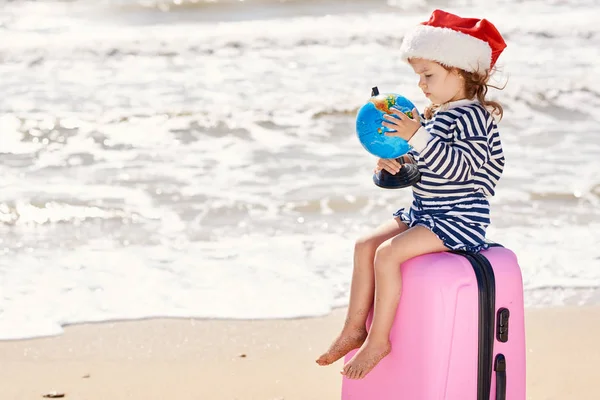 Happy Little Girl Dziecko Santa Kapelusz Walizką Kuli Ziemskiej Tropikalnej — Zdjęcie stockowe