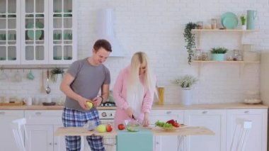 Mutlu adam sebze salatası hazırlıyor. Güzel kız arkadaşına sataşıyor.