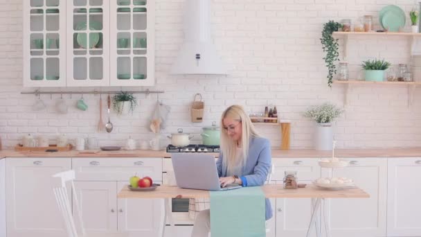 Geschäftsfrau in Brille und Jacke arbeitet am Laptop in der Küche — Stockvideo