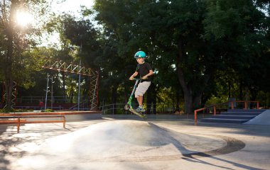 Scooter'lı ve koruyucu kasklı bir çocuk paten parkında inanılmaz gösteriler yapıyor. Aşırı atlayış. Sağlıklı bir yaşam tarzı ve spor eğlence kavramı