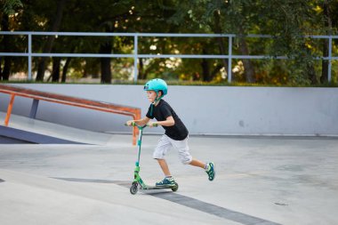 Scooter'lı ve koruyucu kasklı bir çocuk paten parkında inanılmaz gösteriler yapıyor. Aşırı atlayış. Sağlıklı bir yaşam tarzı ve spor eğlence kavramı