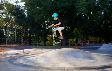 Scooter'lı ve koruyucu kasklı bir çocuk paten parkında inanılmaz gösteriler yapıyor. Aşırı atlayış. Sağlıklı bir yaşam tarzı ve spor eğlence kavramı