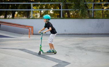 Scooter'lı ve koruyucu kasklı bir çocuk paten parkında inanılmaz gösteriler yapıyor. Aşırı atlayış. Sağlıklı bir yaşam tarzı ve spor eğlence kavramı