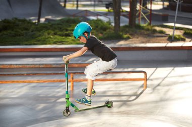 Scooter'lı ve koruyucu kasklı bir çocuk paten parkında inanılmaz gösteriler yapıyor. Aşırı atlayış. Sağlıklı bir yaşam tarzı ve spor eğlence kavramı