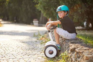 Parkta jimnastik yapan bir çocuk, dengeli bir scooter. Aktif yaşam tarzı teknolojisi gelecek.