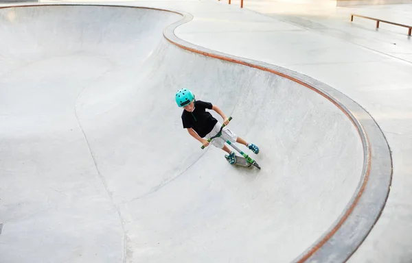 A boy on a scooter and in protective helmet do incredible stunts in skate park. Extreme jump. The concept of a healthy lifestyle and sports leisure