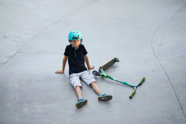 Athletic boy en casco y rodilleras aprende a monopatín en un skate