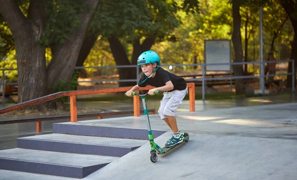 Scooter'lı ve koruyucu kasklı bir çocuk paten parkında inanılmaz gösteriler yapıyor. Aşırı atlayış. Sağlıklı bir yaşam tarzı ve spor eğlence kavramı
