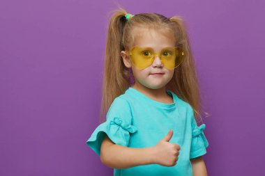 Mor arka planda izole edilmiş küçük kız kalbi şekilli güneş gözlüğü. Onaylandı, her şey yolunda. Mutlu çocukluk, vay ve şok konsepti