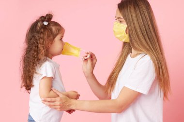 Sevdiklerinle ilgilenmek. Genç anne, Covid-19 salgınında kızına koruyucu bir maske takıyor. Karantinanın sonu