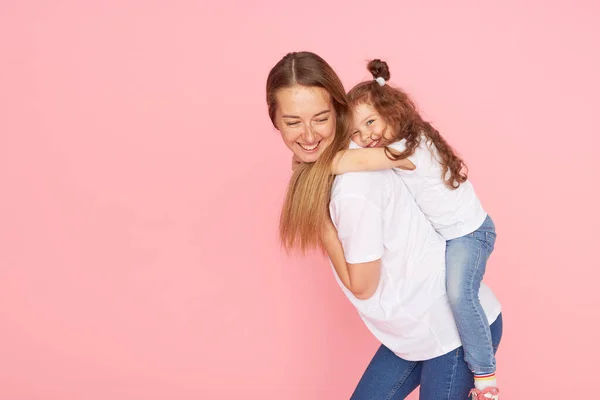 Mama Córka Białych Koszulkach Dżinsach Bawią Się Przytulają Różowym Tle — Zdjęcie stockowe