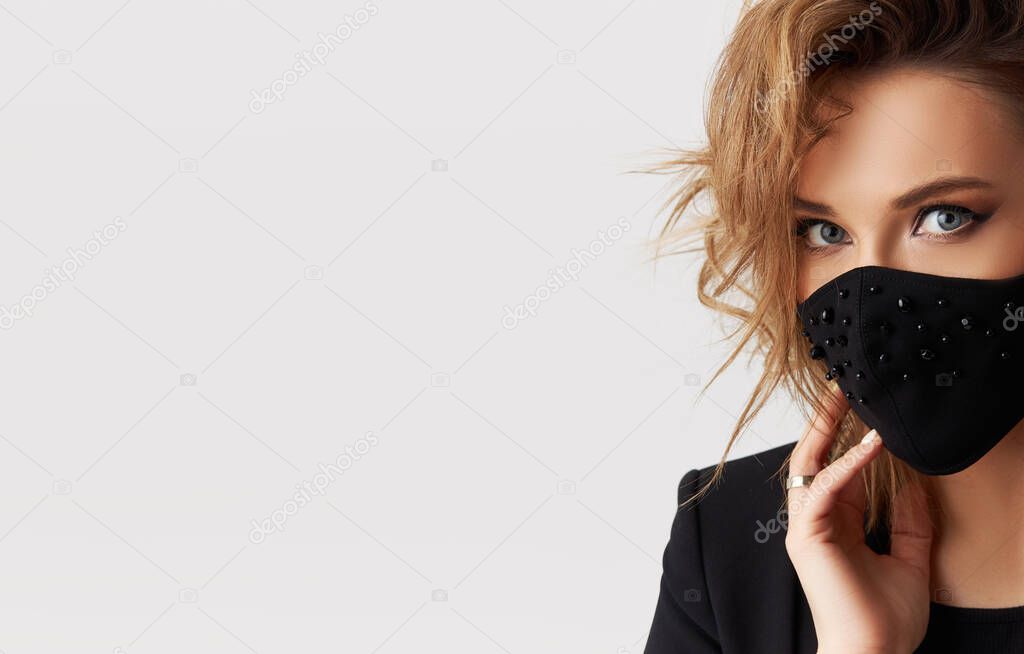 Woman in trendy fashionable outfit during quarantine of coronavirus outbreak. Model dressed stylish black protective face mask on white background