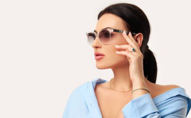 Olası ve modern optik ve lenslerin reklamı. Güneş gözlüklü, beyaz arka planda poz veren güzel bir kadın. Beyaz kadın modelin zarif portresi.