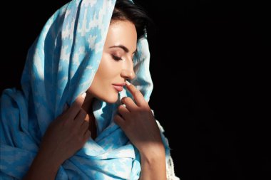 Mavi eşarplı, doğulu genç bir kadın. Mükemmel makyaj ve el yapımı aksesuarları olan Arap ya da Hintli bir kızın güzel portresi.