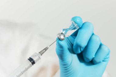 Biyolojik tehlike. Çin koronavirüsü salgını. Koruyucu giysili ve maskeli doktor şırınga ve aşı tutuyor. Grip aşısı, koronavirüs, ebola, tüberküloz. 