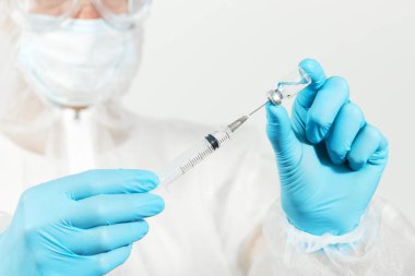 Biyolojik tehlike. Çin koronavirüsü salgını. Koruyucu giysili ve maskeli doktor şırınga ve aşı tutuyor. Grip aşısı, koronavirüs, ebola, tüberküloz. 