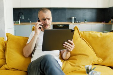 Genç, çekici, gülümseyen adam dizüstü bilgisayarını karıştırıyor evinde rahat bir kanepede oturuyor, günlük kıyafetleriyle. Blogger Serbest Yazıcı