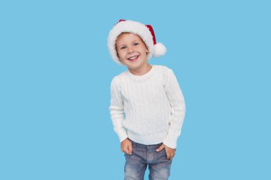 Noel Baba şapkası takmış küçük bir çocuğun portresi. Kahkahalar mavi arka planda