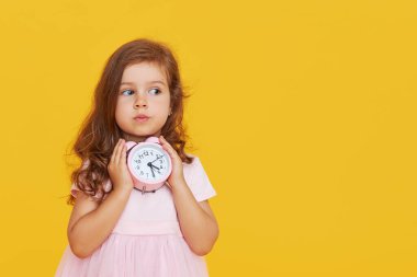 Parti zamanı geldi. Süslü elbiseli düşünceli şirin bir çocuk elinde küçük bir çalar saat tutuyor ve ortaya çıkıyor. Sarı stüdyo arka planı