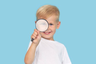 Mavi arka planda büyüteç olan sevimli çocuk. Araştırma ve keşif kavramı. 