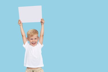 Şirin, gülen bir çocuk elinde mesaj atmak için boş yeri olan beyaz bir tabela tutuyor. Çocuk ürünlerinin reklamları, indirimler ve satışların duyurulması