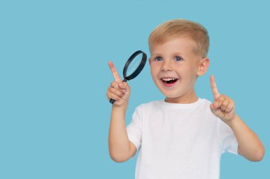 Mavi arka planda büyüteç olan sevimli çocuk. Araştırma ve keşif kavramı. 