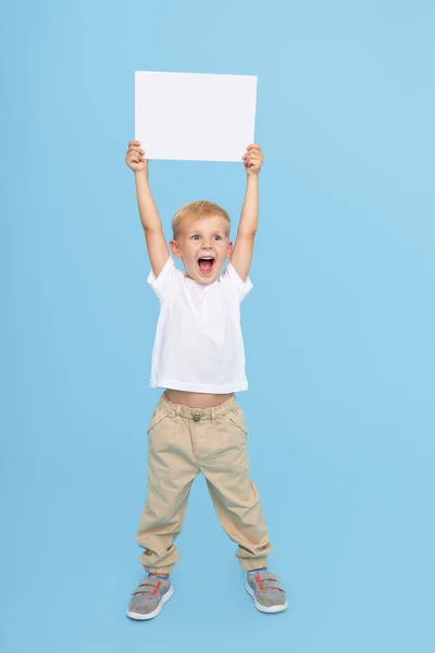 Een Schattige Lachende Jongen Houdt Een Wit Bord Vast Met — Stockfoto