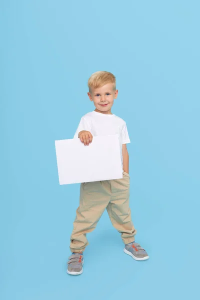 一个可爱的笑着的小男孩拿着一块白色的标牌 上面有一个空的文字空间 儿童用品广告及折扣 销售公告 — 图库照片