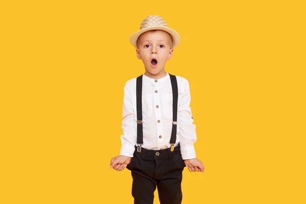 黄色の背景に空のポケットを持つ流行の黒のズボンでスタイリッシュな子供の男の子 — ストック写真
