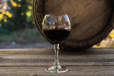 kırmızı şarap şişesi ve şarap kadehi yün fıçıda.