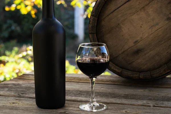 kırmızı şarap şişesi ve şarap kadehi yün fıçıda.