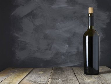 Ahşap arka planda kırmızı şarap şişesi.