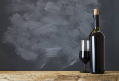 Ahşap arka planda kırmızı şarap şişesi.