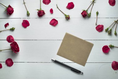 taze kırmızı gül çiçekler, yaprakları, kağıt levha ve beyaz tahta yüzeyi kalem